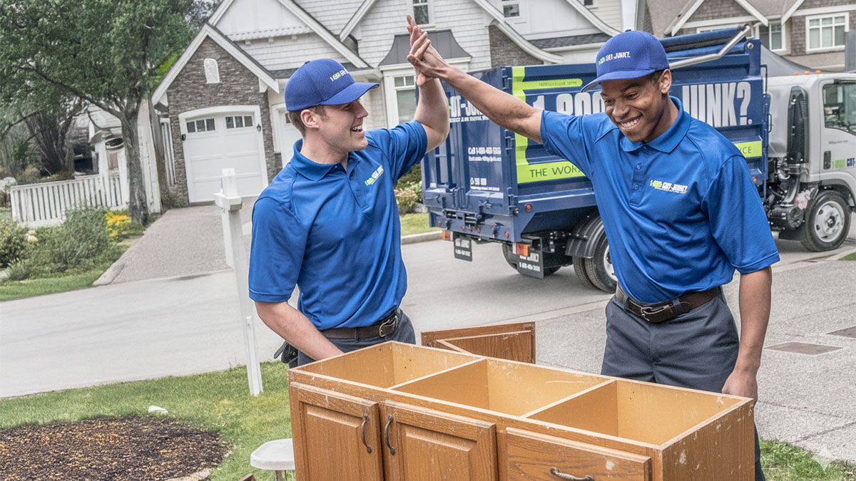 1-800-GOT-JUNK? truck team members removing cabinets and renovation debris from a client’s kitchen.