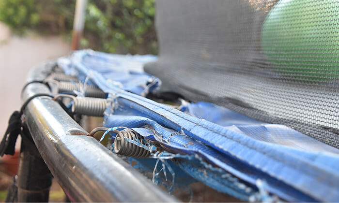 An old trampoline sitting on the curbside for removal and recycling.
